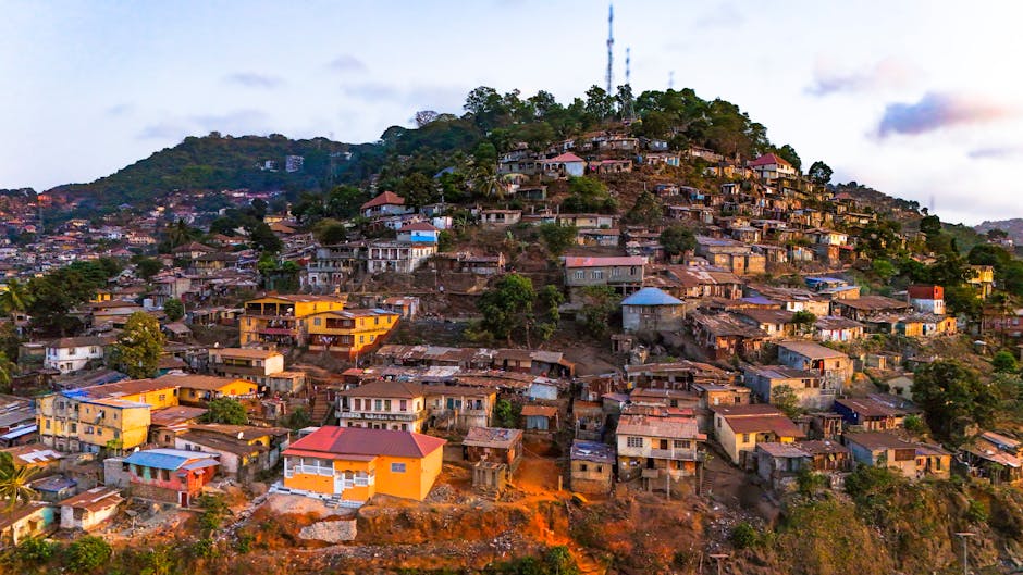 A densely populated hillside community with numerous small houses and buildings constructed close together on a steep slope, featuring a variety of construction materials including concrete, wood, and